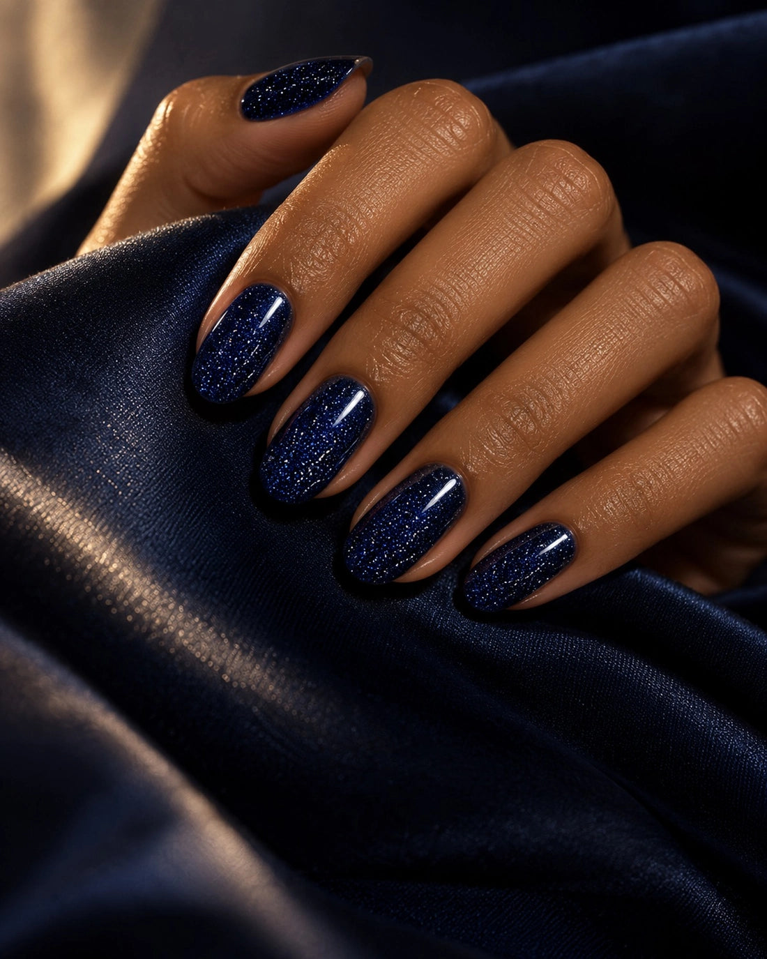 Midnight blue glitter manicure on satin